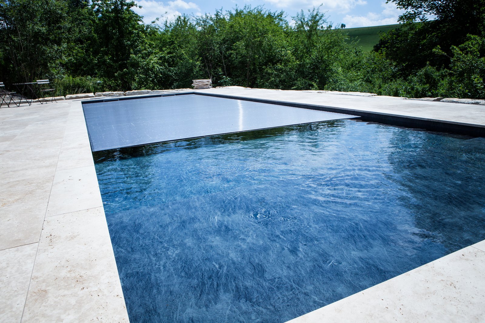 Fertig gebauter Schwimmbad-Pool mit Naturstein-Terrasse und Abdeckung auf der Schwäbischen Alb – eine Eigeninstallation von Schwimmbadbau24